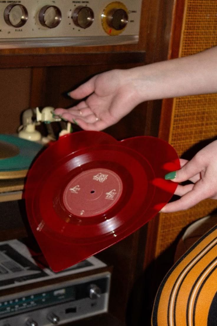 Red translucent heart-shaped vinyl record held gently in hands